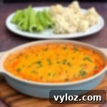 keto low carb buffalo chicken dip in a bowl, plate of celery and cauliflower