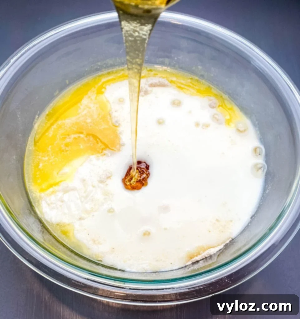 honey poured into a glass bowl with cornbread batter
