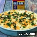 Hot Cream Cheese Old Bay Seafood Crab Dip in a baking dish and a container of old bay seasoning