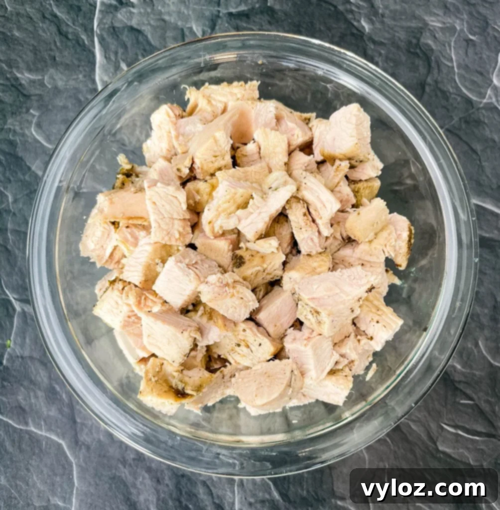 Perfectly cooked and cubed turkey breast, ready to be added to a recipe, presented in a clear glass bowl.
