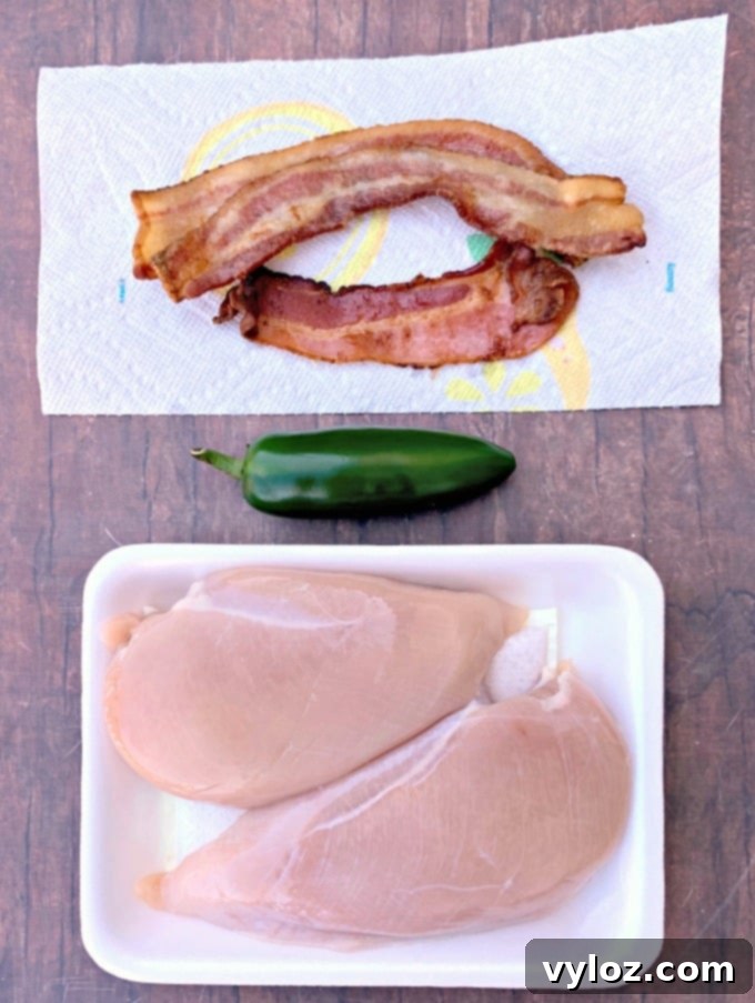 cooked bacon on a paper towel, fresh jalapeno slices, and raw chicken breasts ready for the hasselback technique