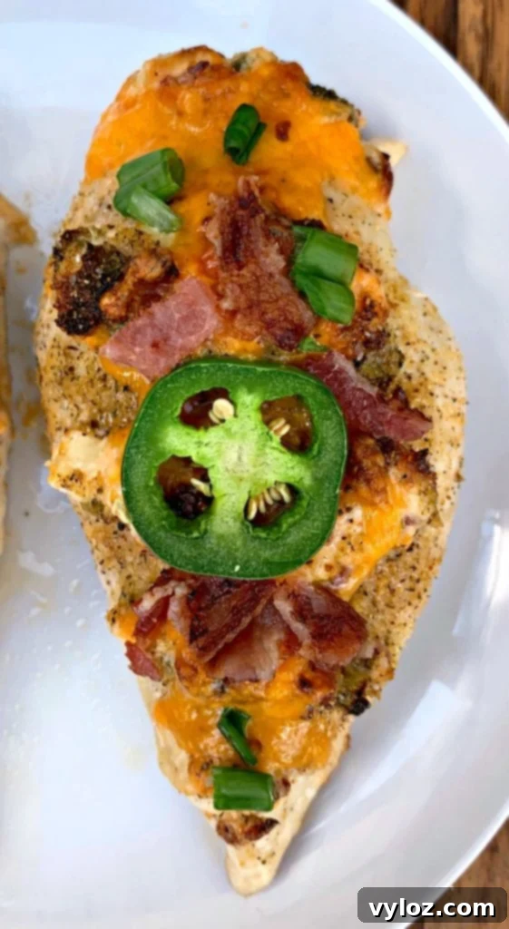 close-up of keto low carb jalapeno popper hasselback chicken on a white plate showing melted cheese and bacon