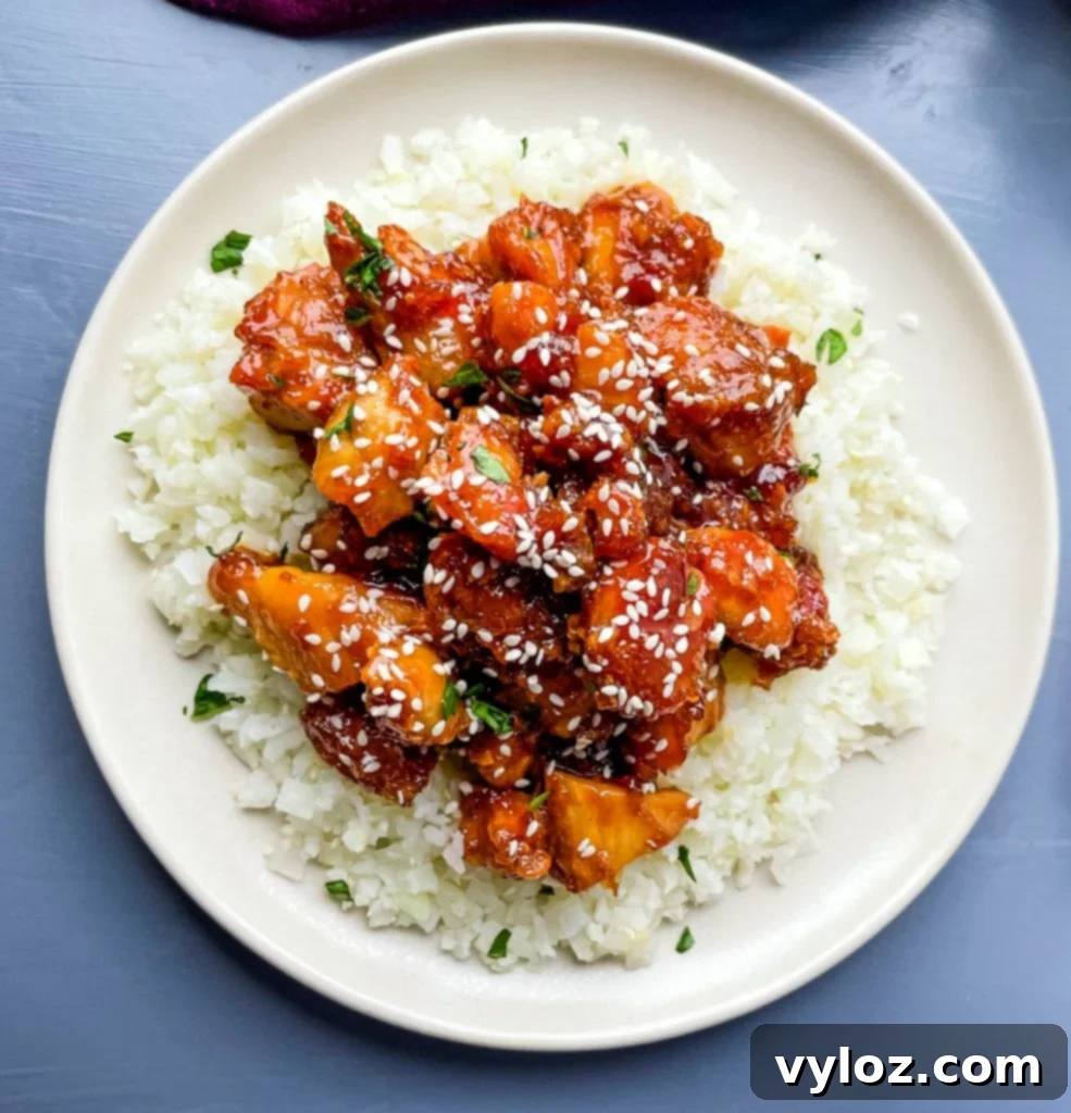 keto low carb orange chicken on a white plate with sesame seeds