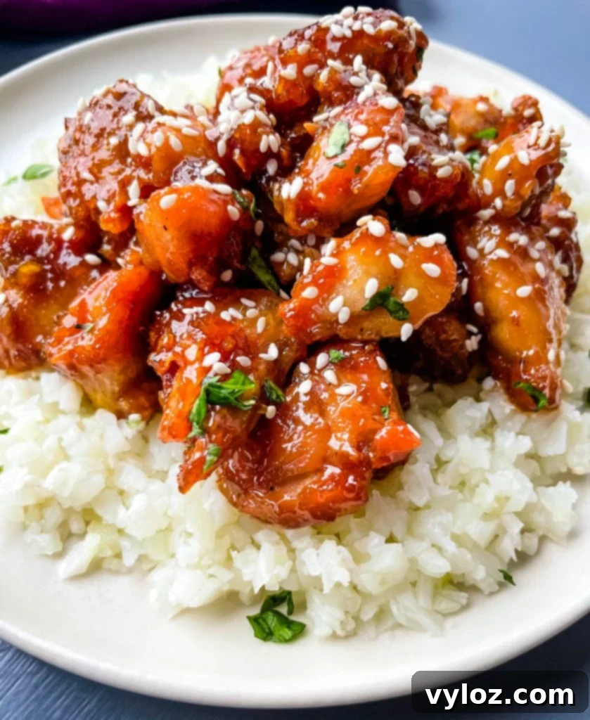 keto low carb orange chicken on a white plate with sesame seeds