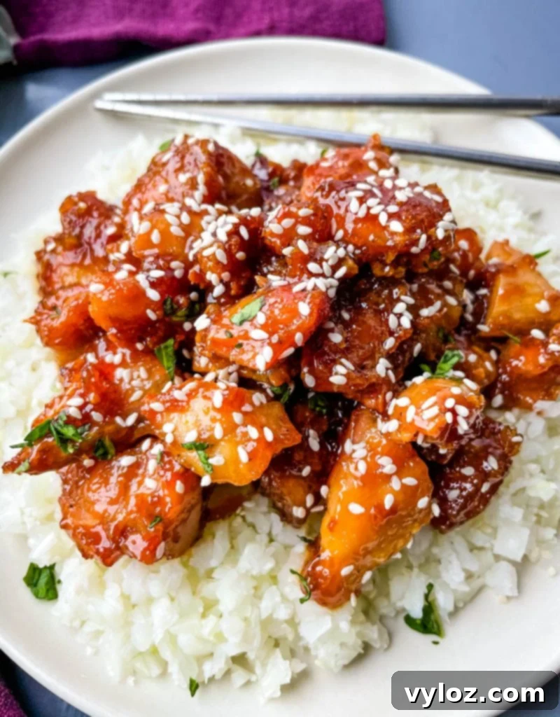 keto low carb orange chicken on a white plate with sesame seeds
