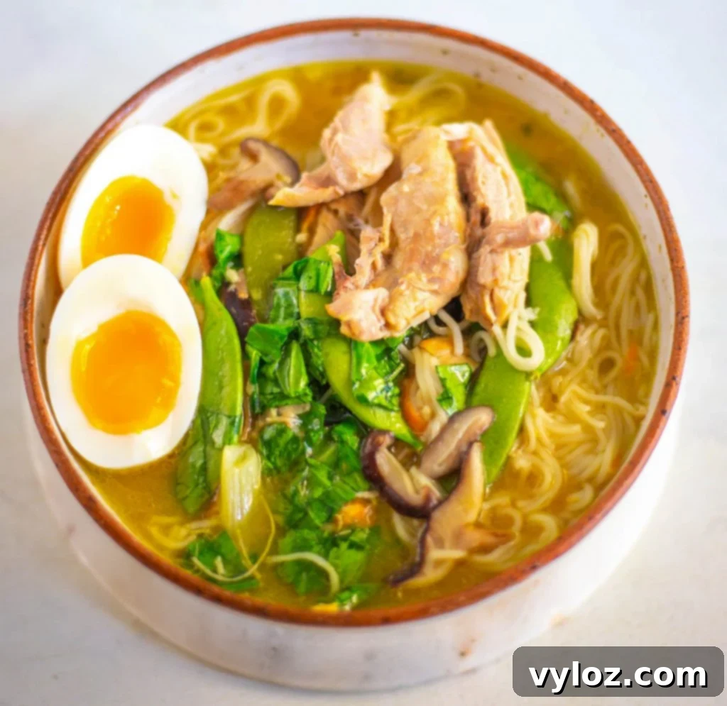 A vibrant bowl of Instant Pot chicken ramen with soft-boiled eggs, green onions, and chili crisp, ready to be enjoyed.