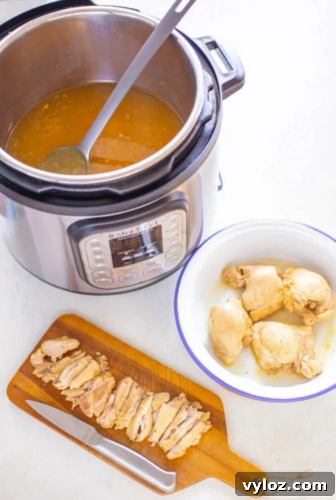 Another view of cooked chicken thighs in an Instant Pot, surrounded by the aromatic broth.