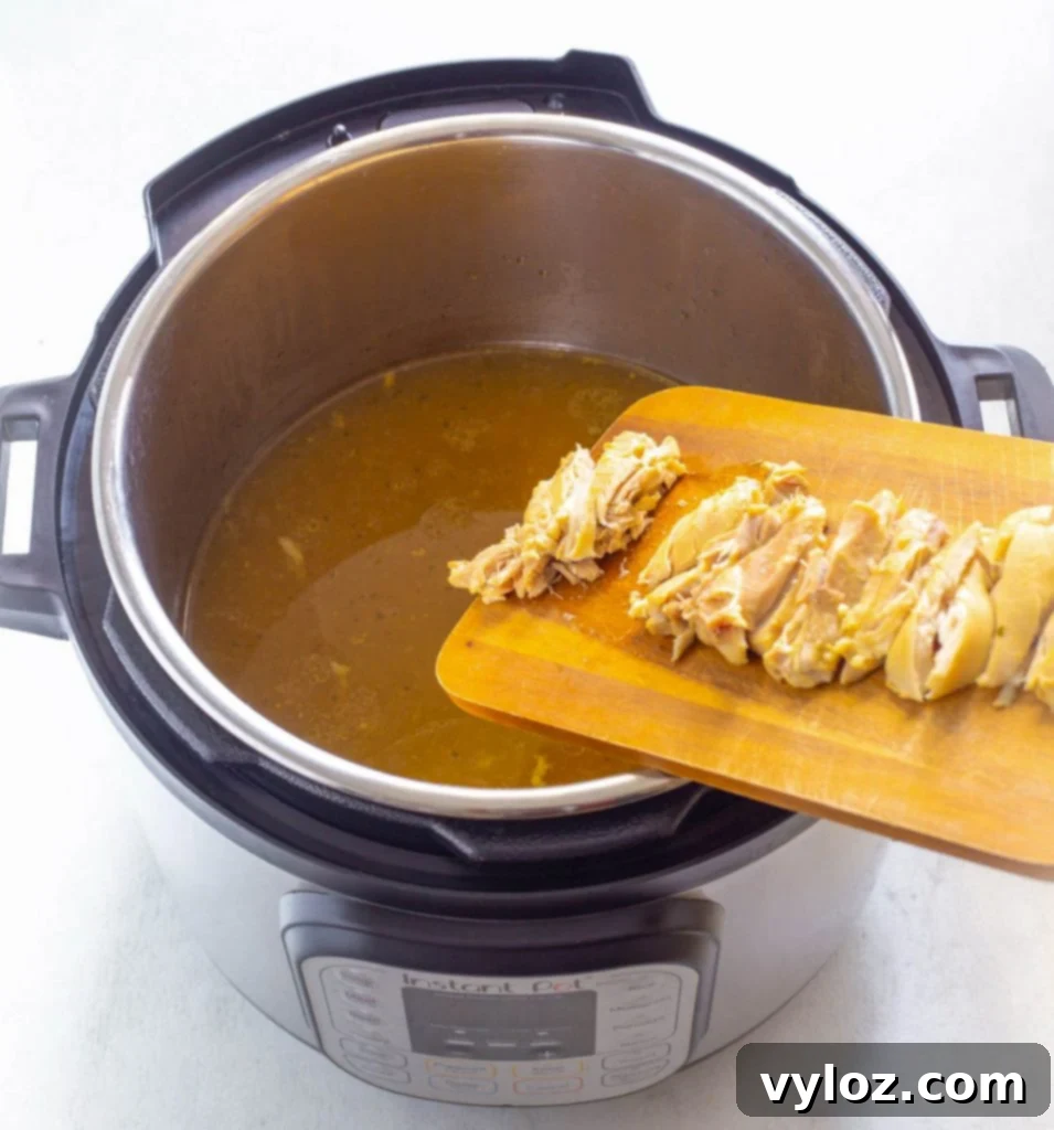 Sliced chicken thighs immersed in the flavorful broth within an Instant Pot, waiting for the final additions.