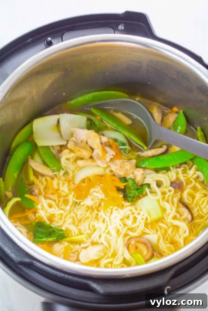Chicken ramen and broth simmering in an Instant Pot, nearly ready to be served.