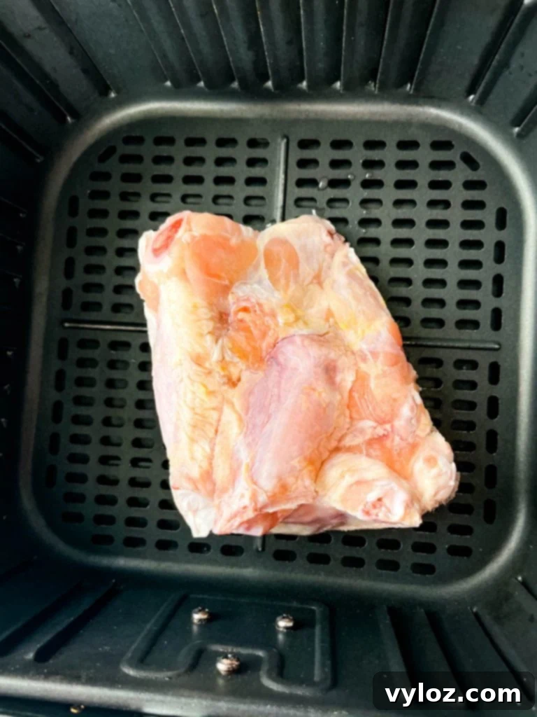Frozen chicken wings being placed in the air fryer basket