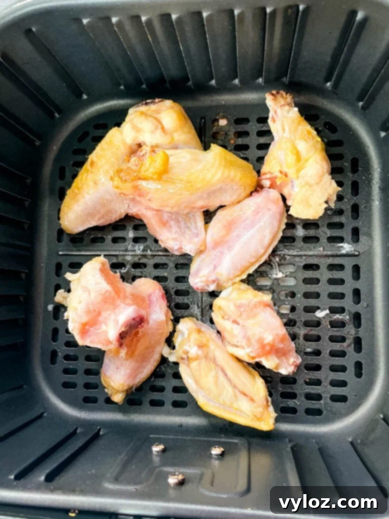 Partially cooked frozen chicken wings in the air fryer after initial cooking