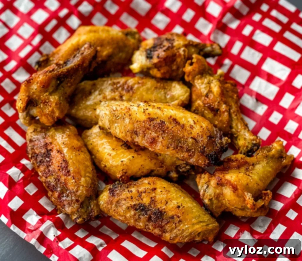 Air fryer chicken wings in a red and white basket, garnished and ready to serve