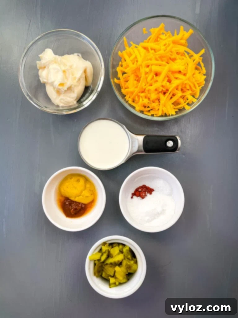 Big Mac Bake 4 A selection of Big Mac Casserole sauce ingredients arranged in glass bowls: creamy mayo, rich shredded cheddar cheese, thick heavy cream, tangy mustard, and finely chopped pickles, showcasing their individual textures.