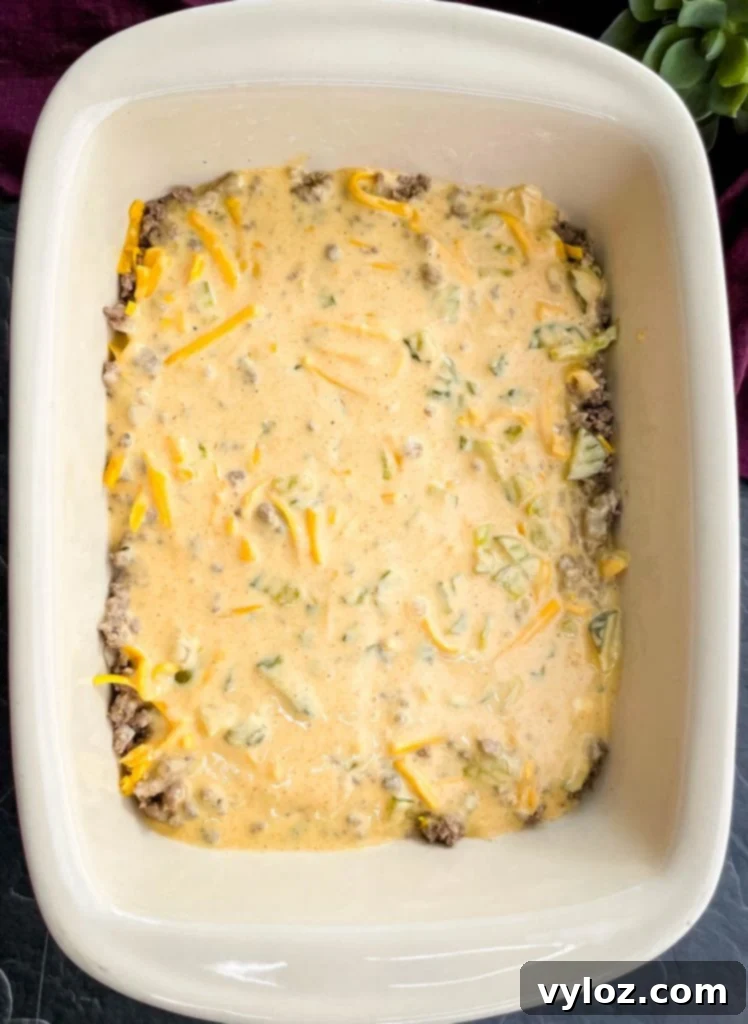 Big Mac Bake 9 The casserole dish with the ground beef and first layer of cheese, now drizzled with the creamy Big Mac Sauce mixture, ready for the final cheese topping.