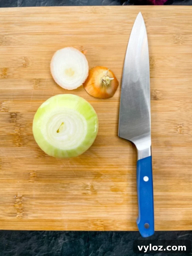 Crispy Keto Low-Carb Onion Rings 4 A large, perfectly peeled raw Vidalia onion sits on a wooden cutting board, ready to be sliced into rings for the keto onion ring recipe.
