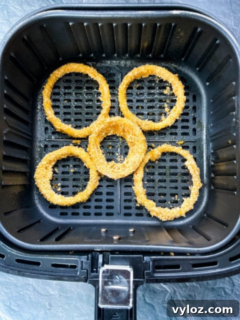 Crispy Keto Low-Carb Onion Rings 7 Golden-brown keto onion rings cooking inside an air fryer basket, demonstrating the air frying method for optimal crispiness.