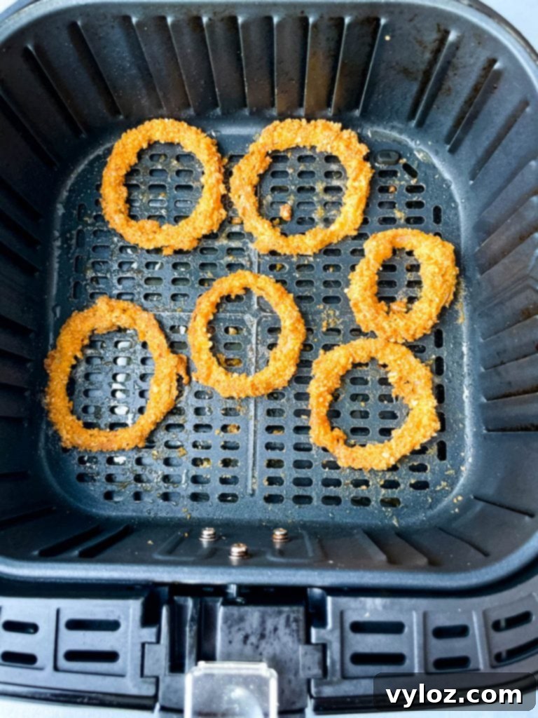 Crispy Keto Low-Carb Onion Rings 8 A close-up shot of perfectly cooked keto onion rings resting in the basket of an air fryer, highlighting their golden-brown color and crispy texture.