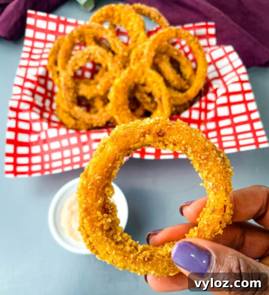 Crispy Keto Low-Carb Onion Rings 9 A person holding a single crispy keto low carb onion ring, showcasing its perfect golden-brown coating and inviting texture.
