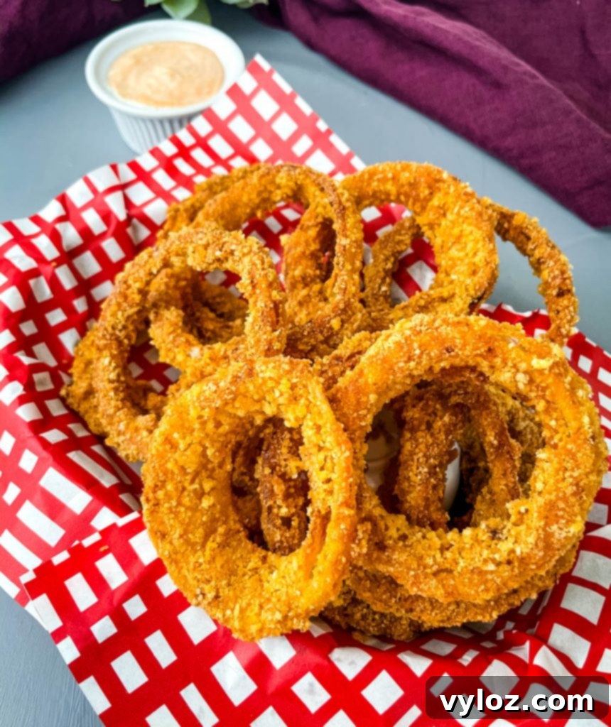 Crispy Keto Low-Carb Onion Rings 10 An appetizing close-up of keto low carb onion rings nestled in a rustic red and black basket, garnished and ready to serve.