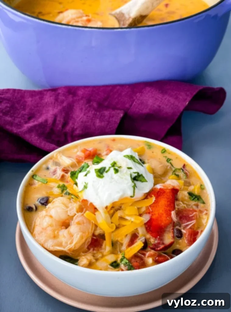 A beautifully topped bowl of creamy seafood chili with shrimp and lobster, garnished with fresh cilantro and a swirl of cream.