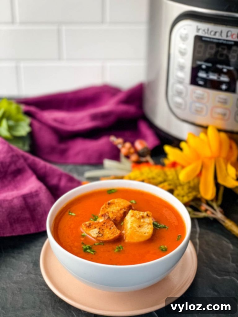 Instant Pot tomato soup in a white bowl with basil garnish