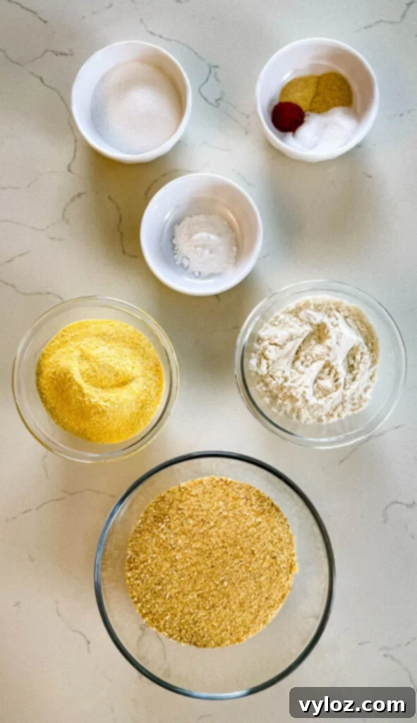 cornmeal, flour, baking powder, seasonings, and sweetener in separate bowls on a flat surface