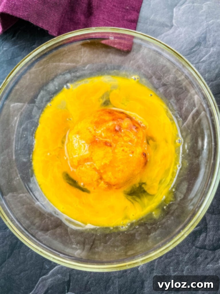 a hushpuppy dredged in raw egg in a glass bowl