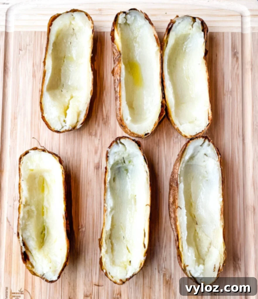 Baked Russet potatoes sliced in half on a cutting board, ready to be scooped