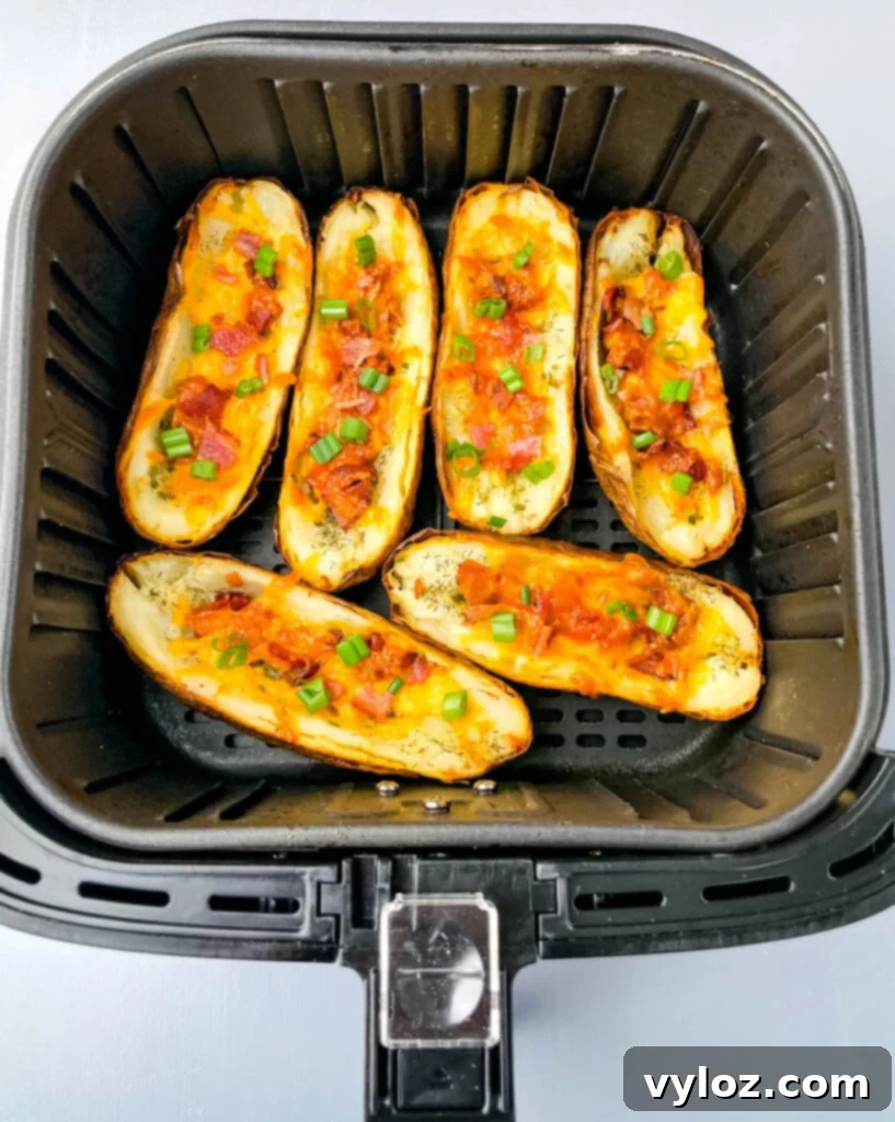 Potato skins loaded with toppings, cooking in an air fryer basket