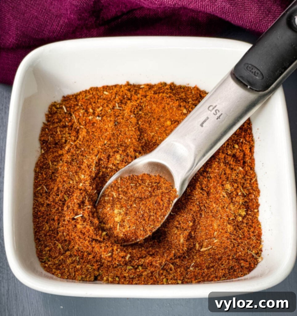 DIY Chili Spice Blend 2 Homemade chili seasoning in a white bowl with a spoon, ready to be used in various dishes.