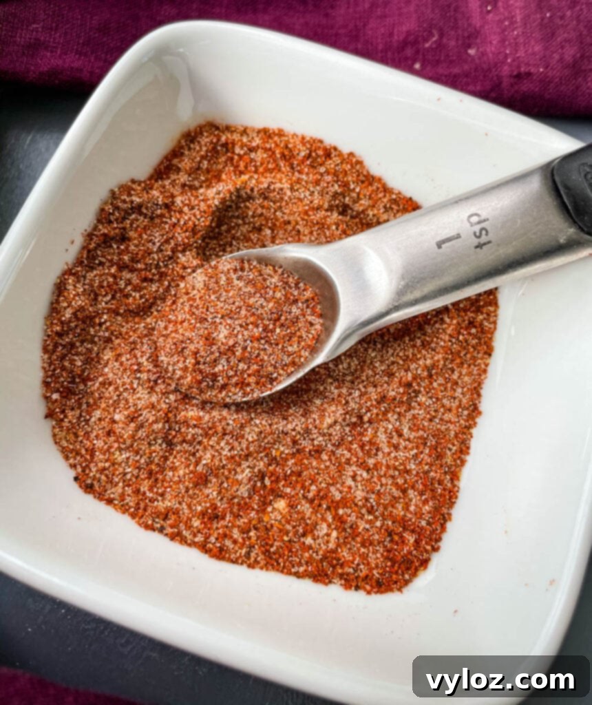 Homemade BBQ seasoning in a white bowl with a spoon
