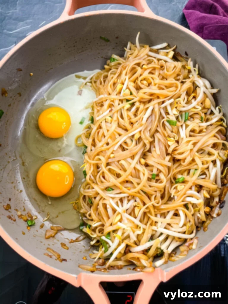 healthy pad thai with chicken, shrimp, bean sprouts, and lime in a pan with raw eggs