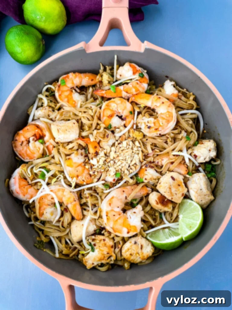 healthy pad thai with chicken, shrimp, bean sprouts, and lime in a pan