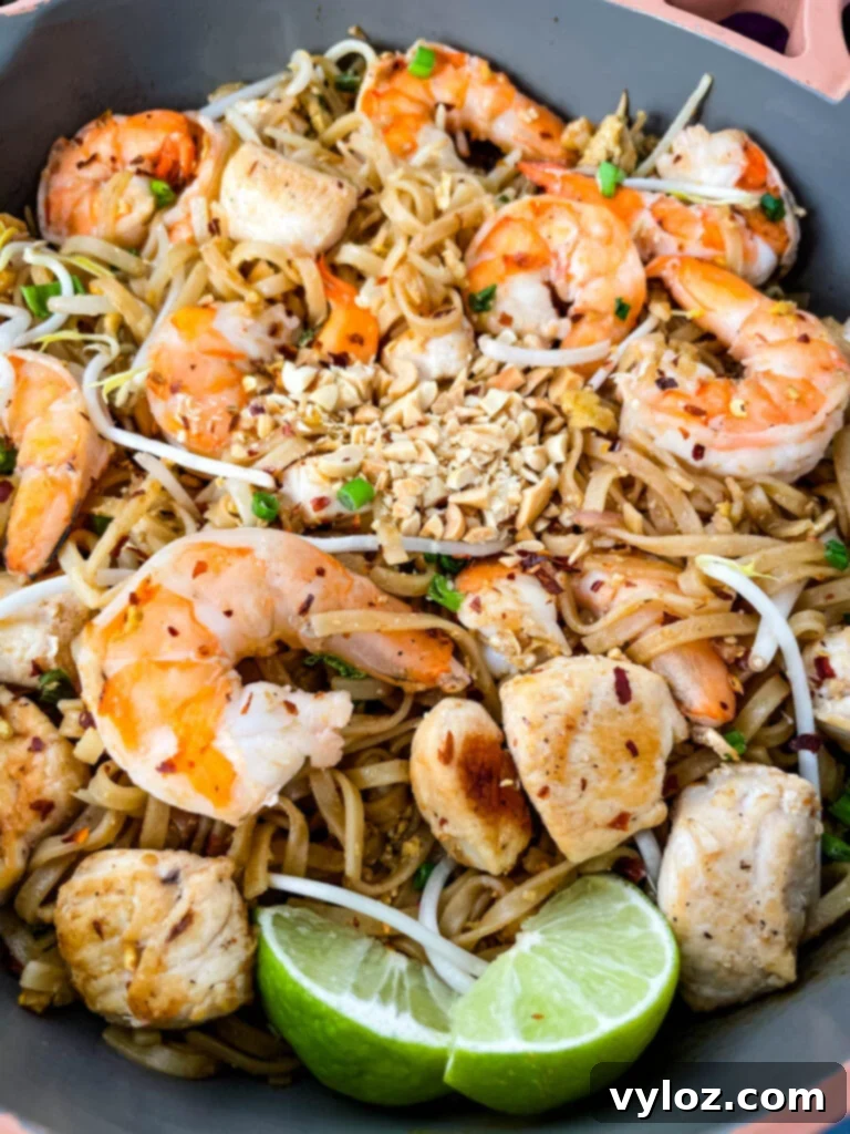 healthy pad thai with chicken, shrimp, bean sprouts, and lime in a pan