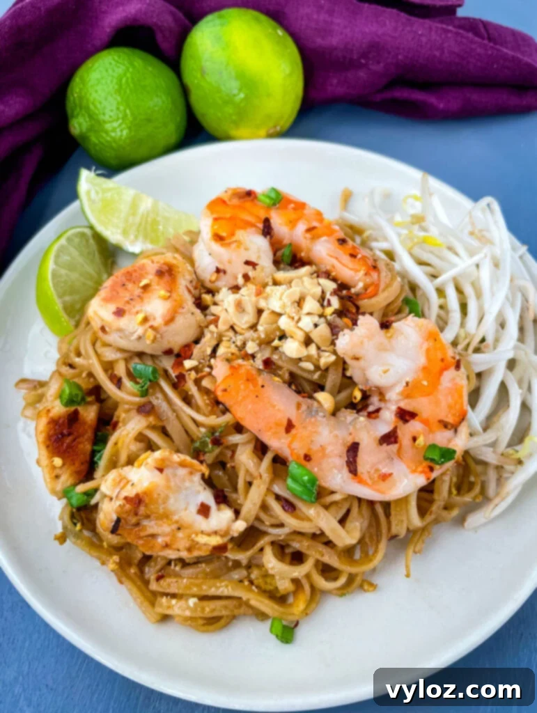 healthy pad thai with chicken, shrimp, bean sprouts, and lime on a white plate