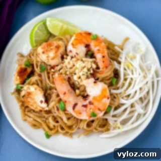 healthy pad thai with chicken, shrimp, bean sprouts, and lime on a white plate
