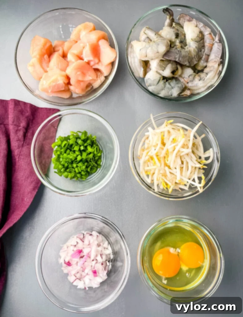 raw chicken, raw shrimp, chopped green onions, bean sprouts, chopped onions, and raw eggs in separate glass bowls