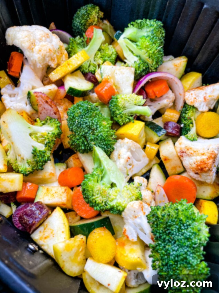 Perfectly air-fried squash, zucchini, onions, carrots, broccoli, and cauliflower, glistening and ready to serve, still in the air fryer basket.