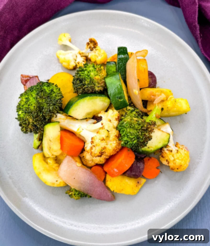 A close-up shot of perfectly roasted air fryer vegetables served on a pristine white plate, showcasing their golden-brown edges and vibrant colors.