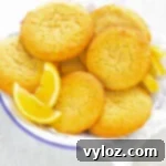 Zesty Sugar-Free Lemon Delights 11 keto low carb lemon cookies on a white plate with lemon wedges