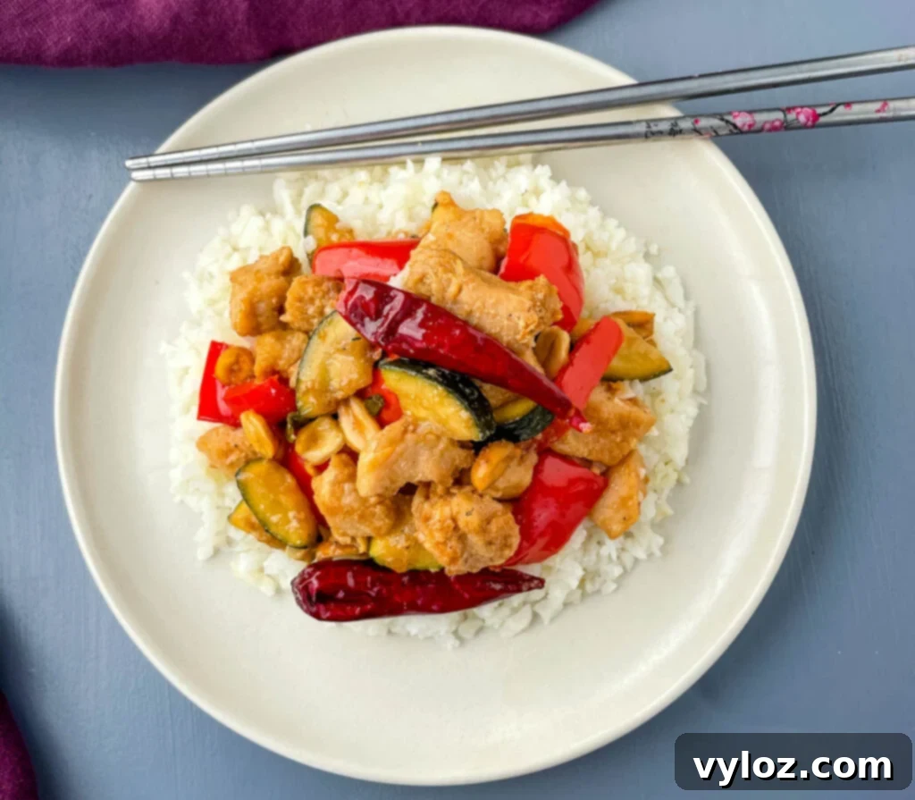 Panda Express copycat kung pao chicken on a white plate with chopsticks, inviting to eat.