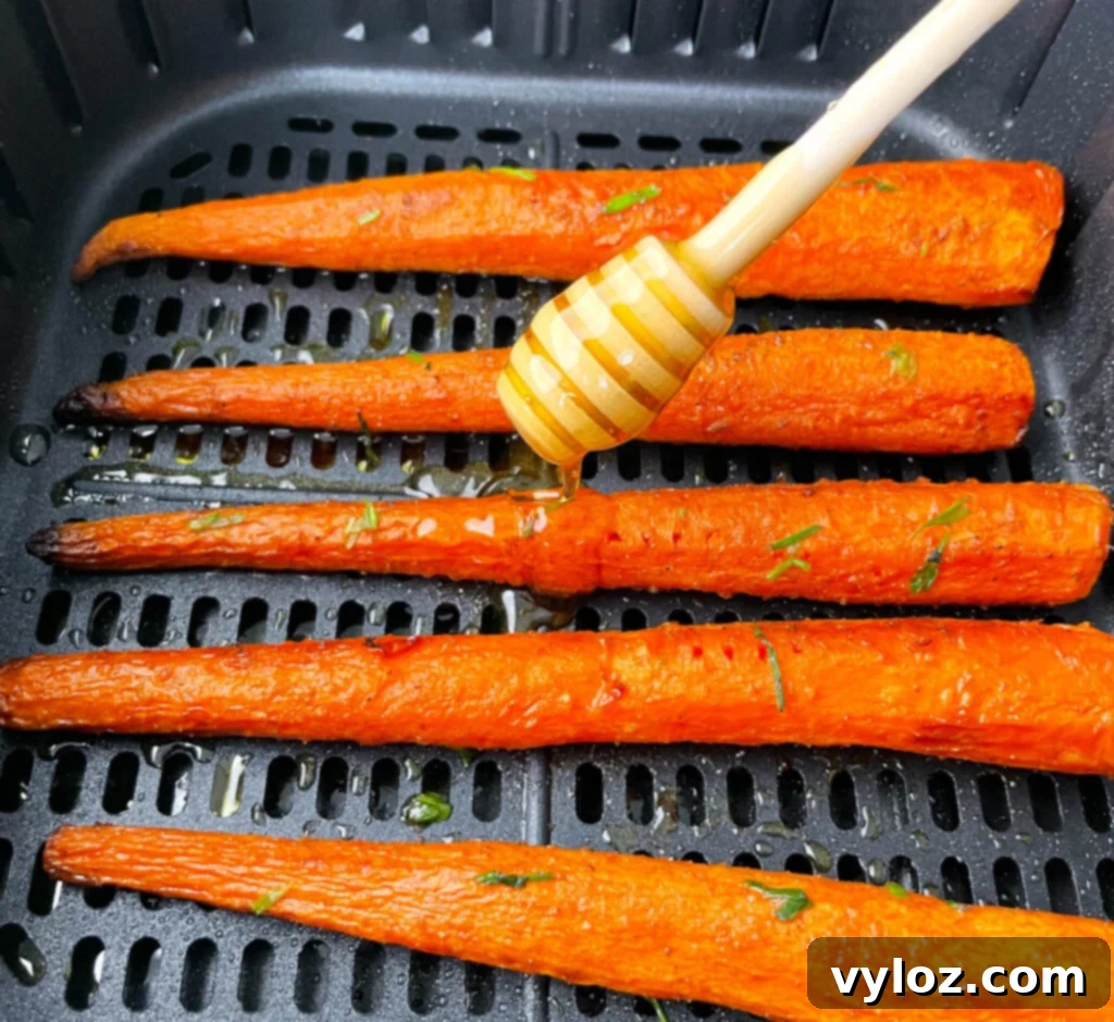 Golden brown roasted carrots in an air fryer basket, glistening with a sweet honey glaze