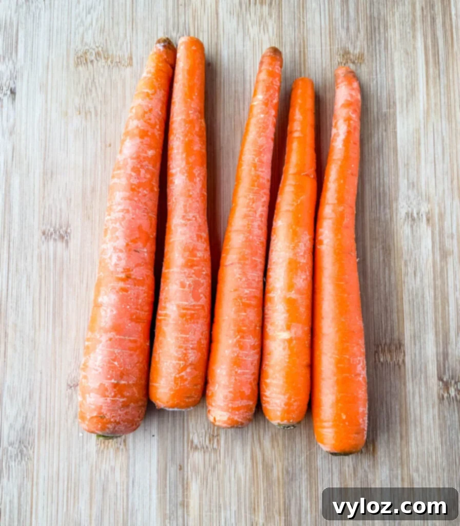 Fresh, vibrant raw carrots laid out on a wooden cutting board, ready for preparation