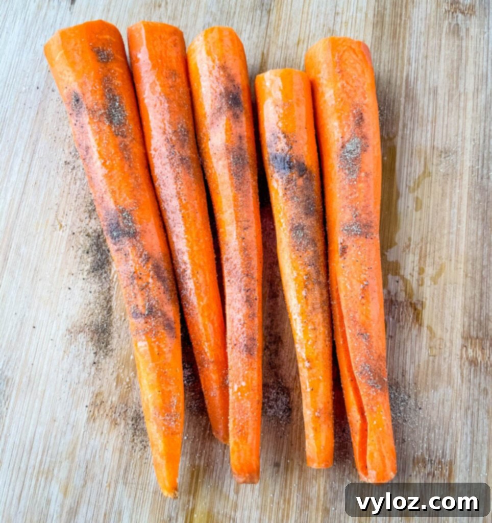 Raw carrots, freshly peeled and seasoned with a blend of aromatic spices like thyme, garlic powder, and paprika, laid on a cutting board
