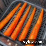 Close-up of roasted carrots in an air fryer basket, showing their appealing texture and color