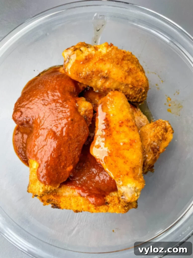 keto chicken wings in a glass bowl with maple syrup and BBQ sauce