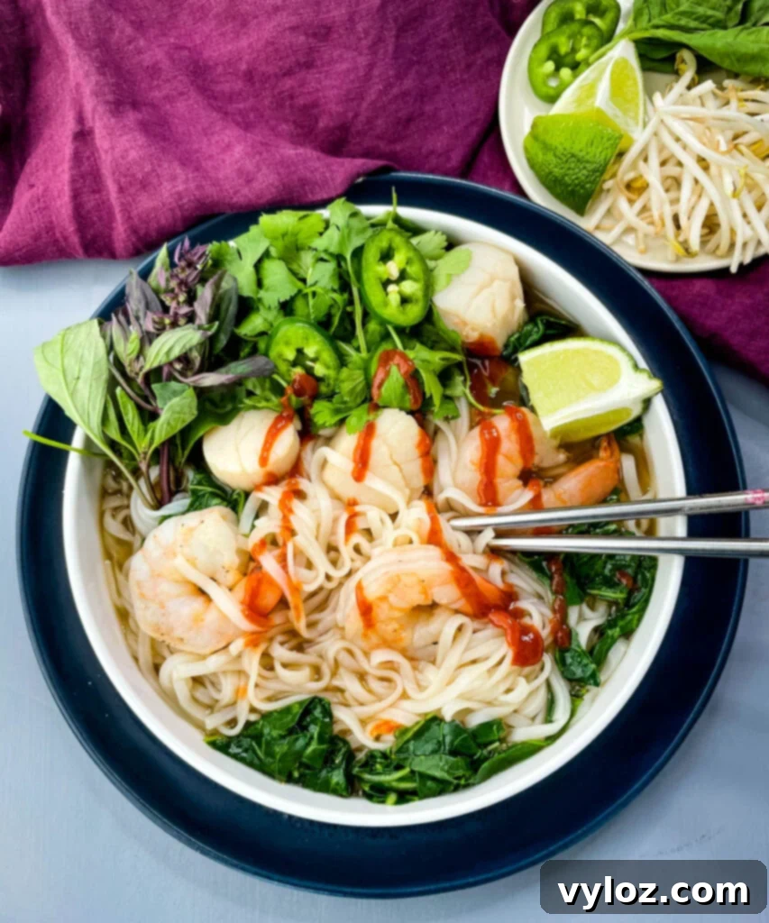 seafood shrimp pho in a white bowl drizzled with Sriracha