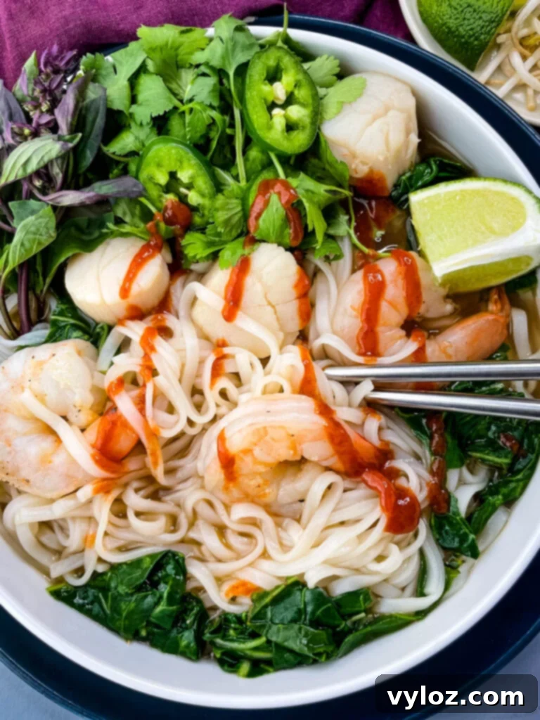 seafood shrimp pho in a white bowl drizzled with Sriracha