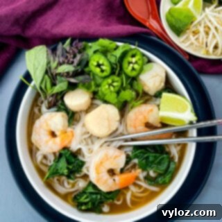 seafood shrimp pho in a white bowl drizzled with Sriracha