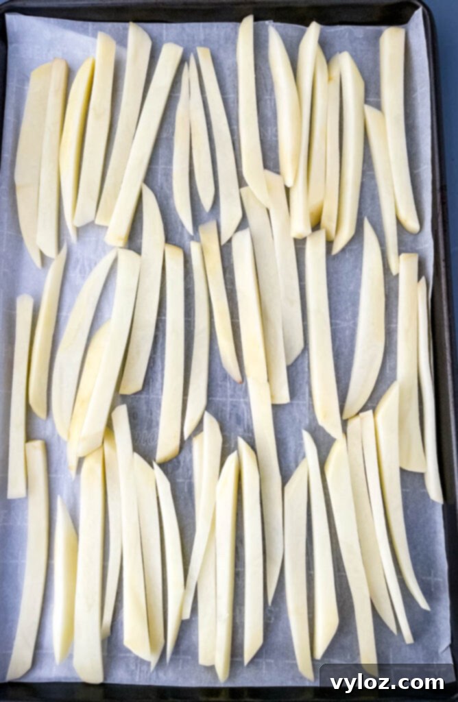 raw sliced potatoes on a sheet pan